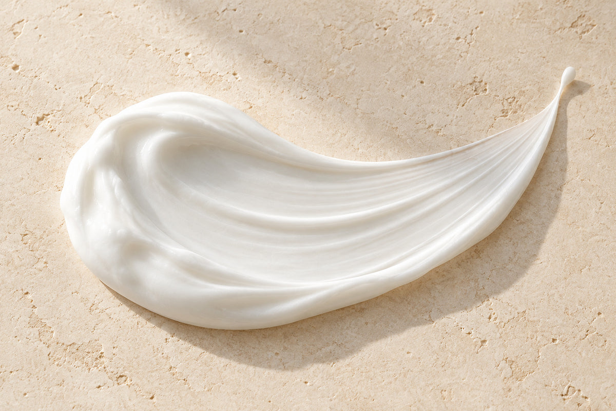 White skincare cream texture on pale stone